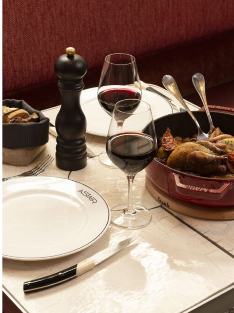 Table dressée avec verres de vin rouge et plat mijoté servi dans une ambiance chaleureuse au restaurant LaCour à Paris
